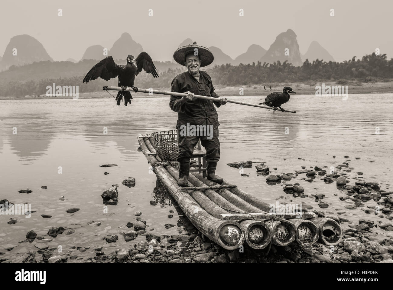 Cormorano pescatore con bambù antica barca sul fiume Li in Yangshuo, Guangxi, Cina Foto Stock