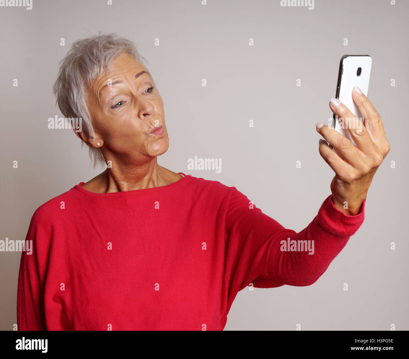 Donna matura prendendo uno smartphone selfie con faccia di anatra Foto Stock