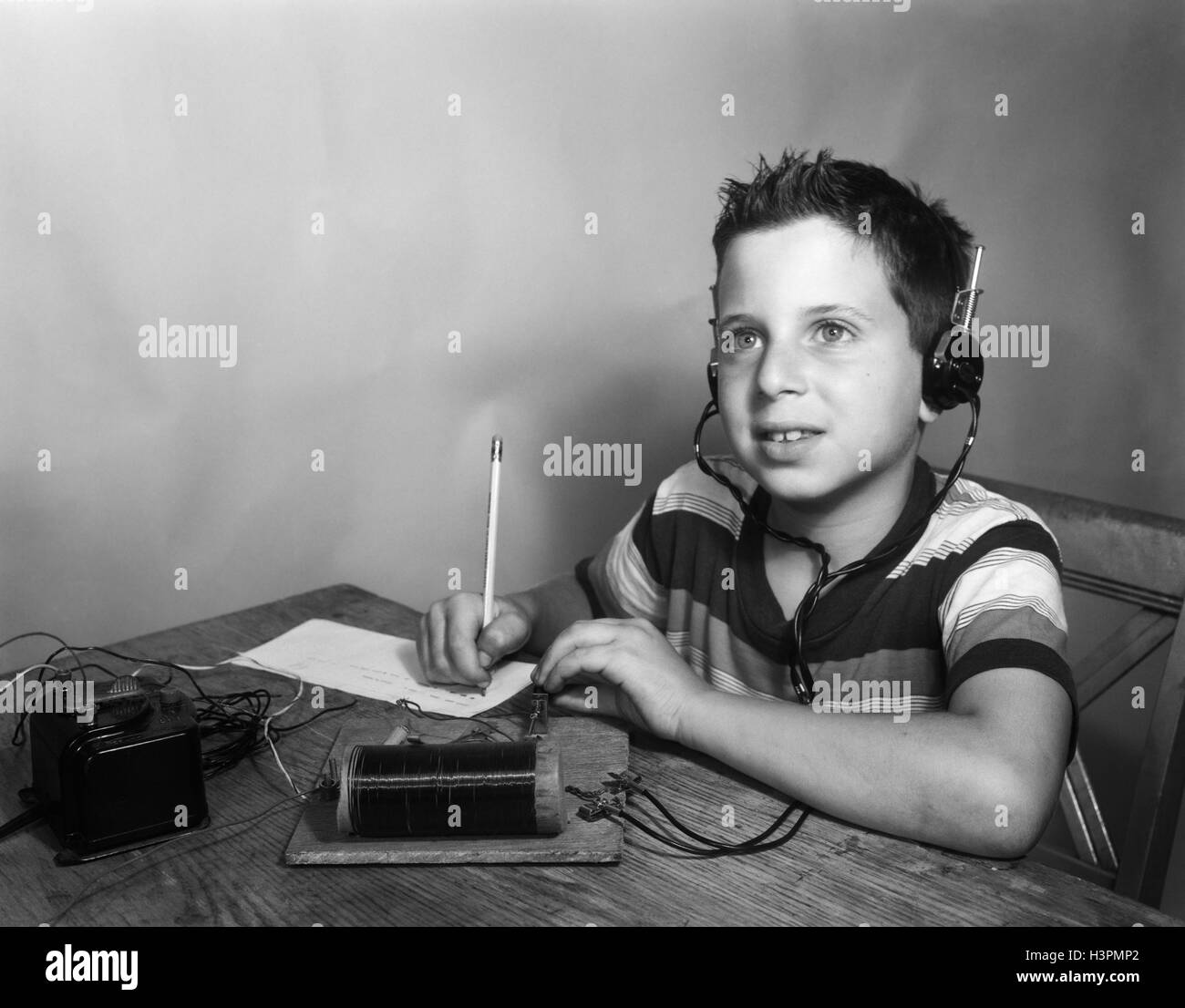 Trenta anni quaranta anni cinquanta giovane ragazzo che indossa le cuffie ascoltando la trascrizione del codice morse dalla radio di cristallo Foto Stock