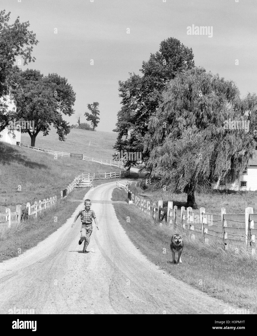 Anni Cinquanta BOY correre giù Vicolo del paese CON IL SUO CANE Foto Stock