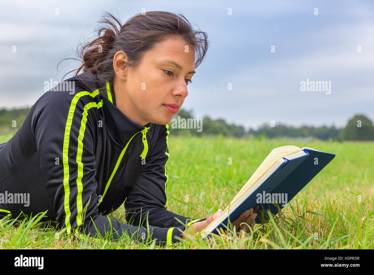 Donna europea giacente in erba libro di lettura Foto Stock