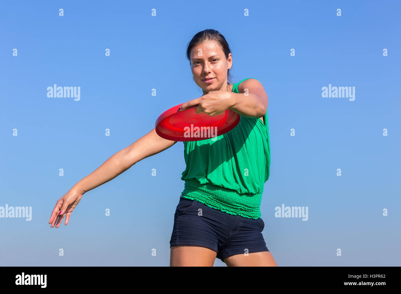 Donna europea gettando frisbee disc in blu cielo privo di nuvole Foto Stock