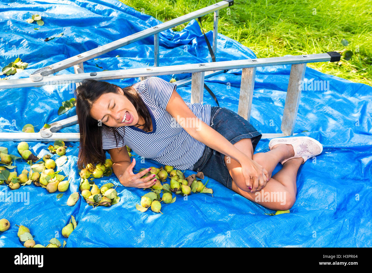 Caduto giovane donna giaceva ferito a terra vicino alla scaletta e pere Foto Stock