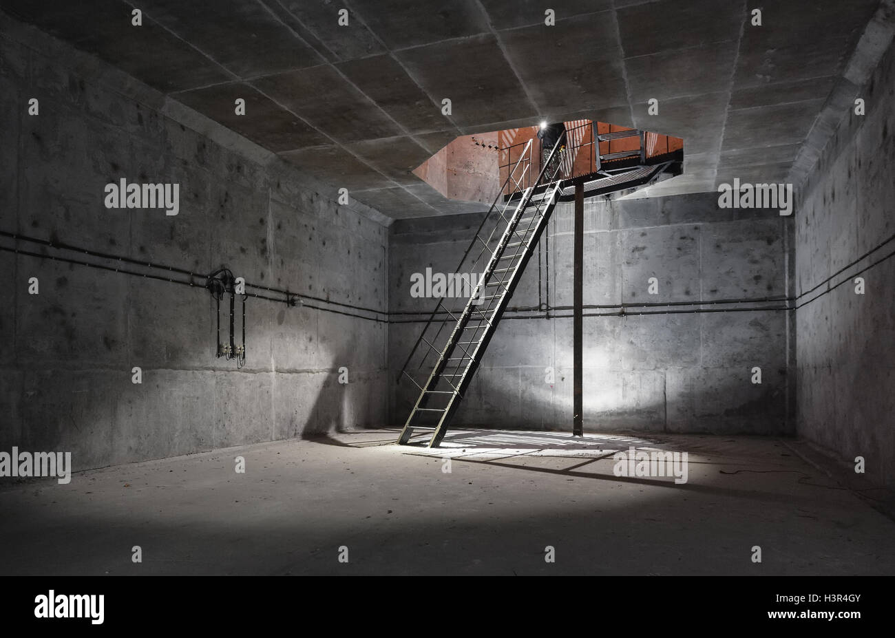 Camera di cemento sotto la terra con una scala alla superficie da cui proviene la luce. Sala tecnica dell'albero di ventilazione del unde Foto Stock