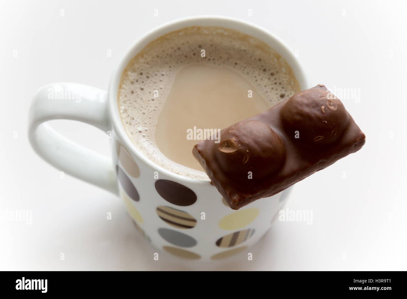 Wafer con glassa di cioccolato sulla parte superiore di una tazza di caffè e latte contro uno sfondo bianco Foto Stock