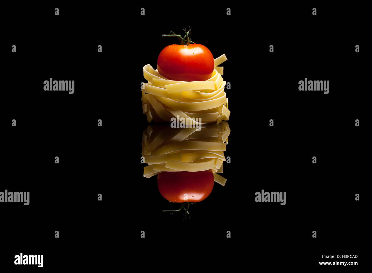 Nido con pasta al pomodoro rosso isolato nero su sfondo riflettente Foto Stock