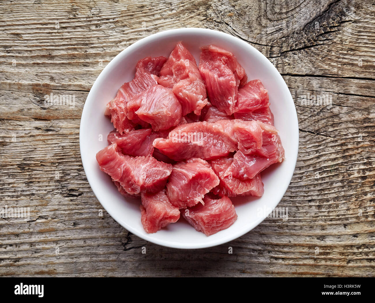 Ciotola bianco di materie a dadini di carne di manzo sul tavolo di legno, vista dall'alto Foto Stock