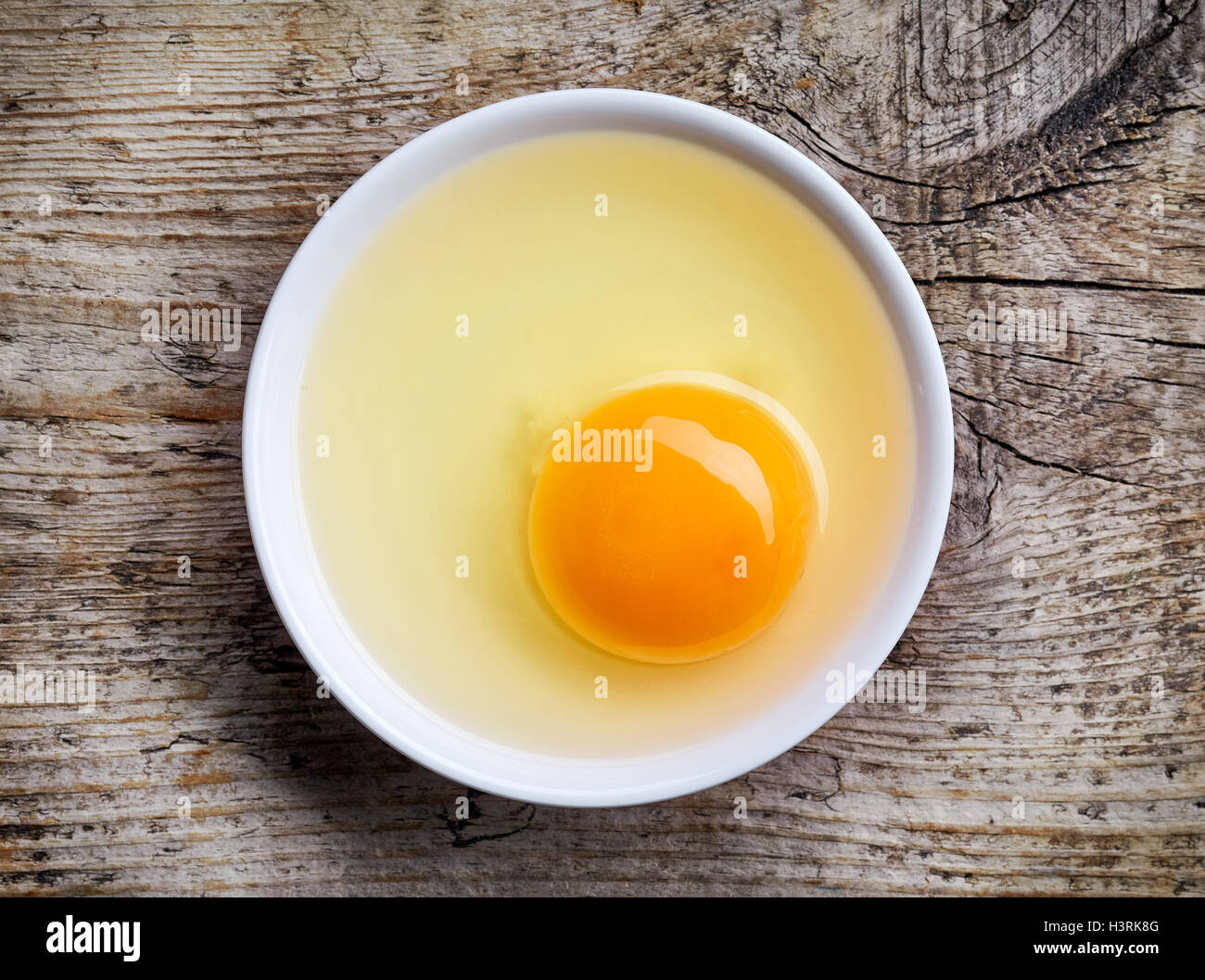 Tuorlo d'uovo in bianco ciotola sul tavolo di legno, vista dall'alto Foto Stock