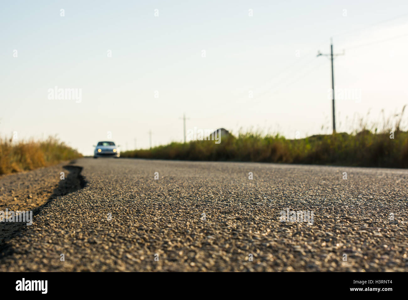 Dettaglio dell'asfalto di una strada di campagna mentre un auto l'aproaches. Foto Stock