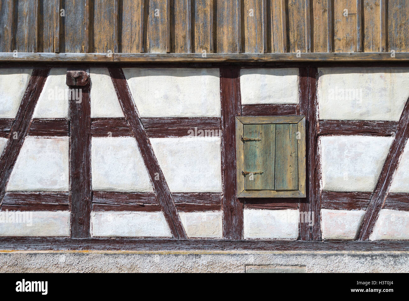 Vecchio a struttura mista in legno e muratura facciata con un finestrino chiuso l'otturatore Foto Stock