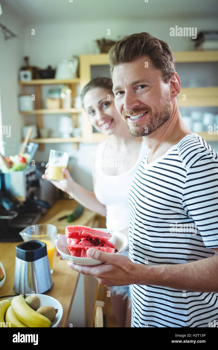 Coppia sorridente piastra di contenimento di acqua il melone in cucina Foto Stock