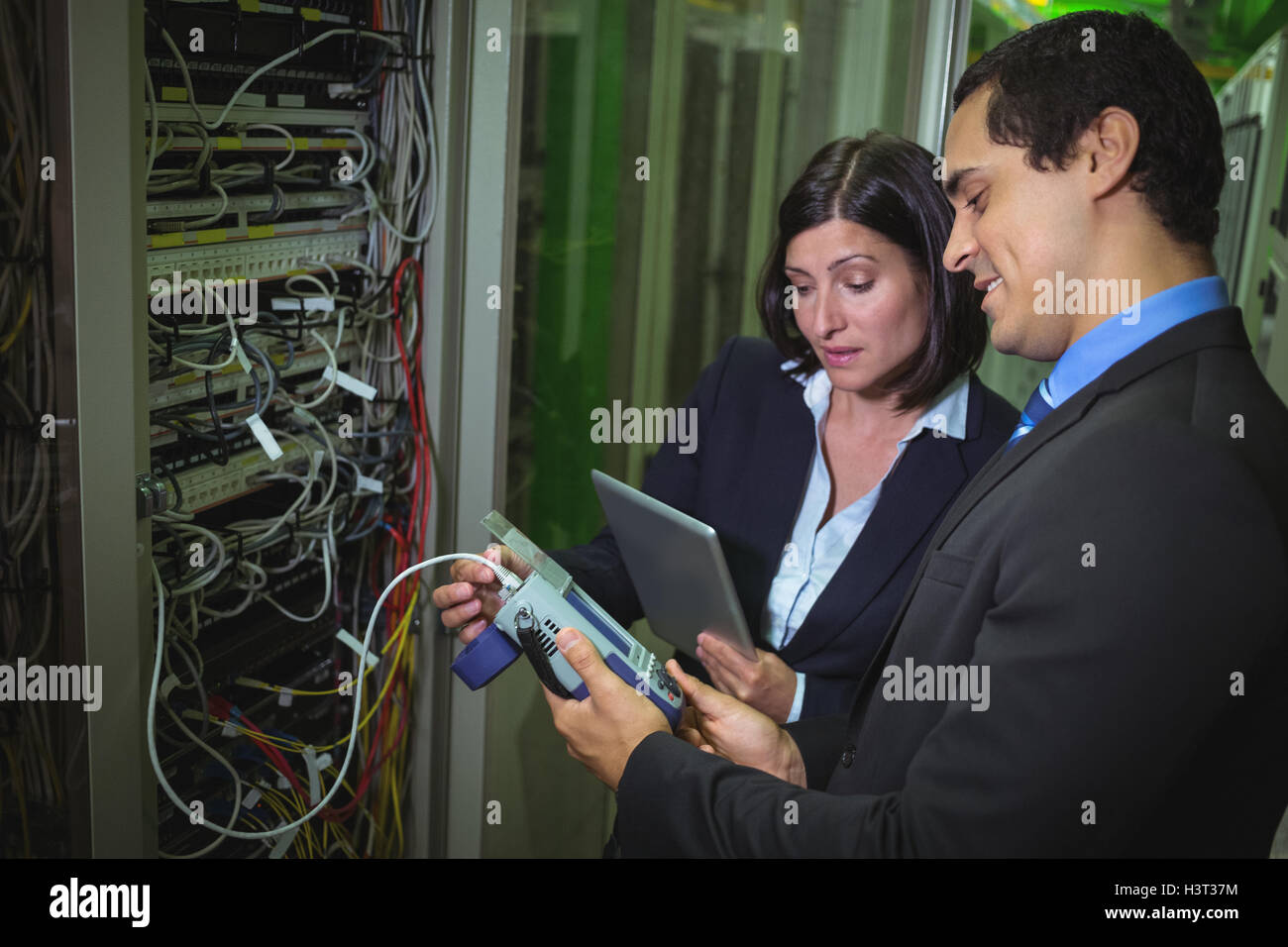 Tecnico che lavora su personal computer mentre analizzando i tecnici del server utilizzando il cavo digitale analy Foto Stock