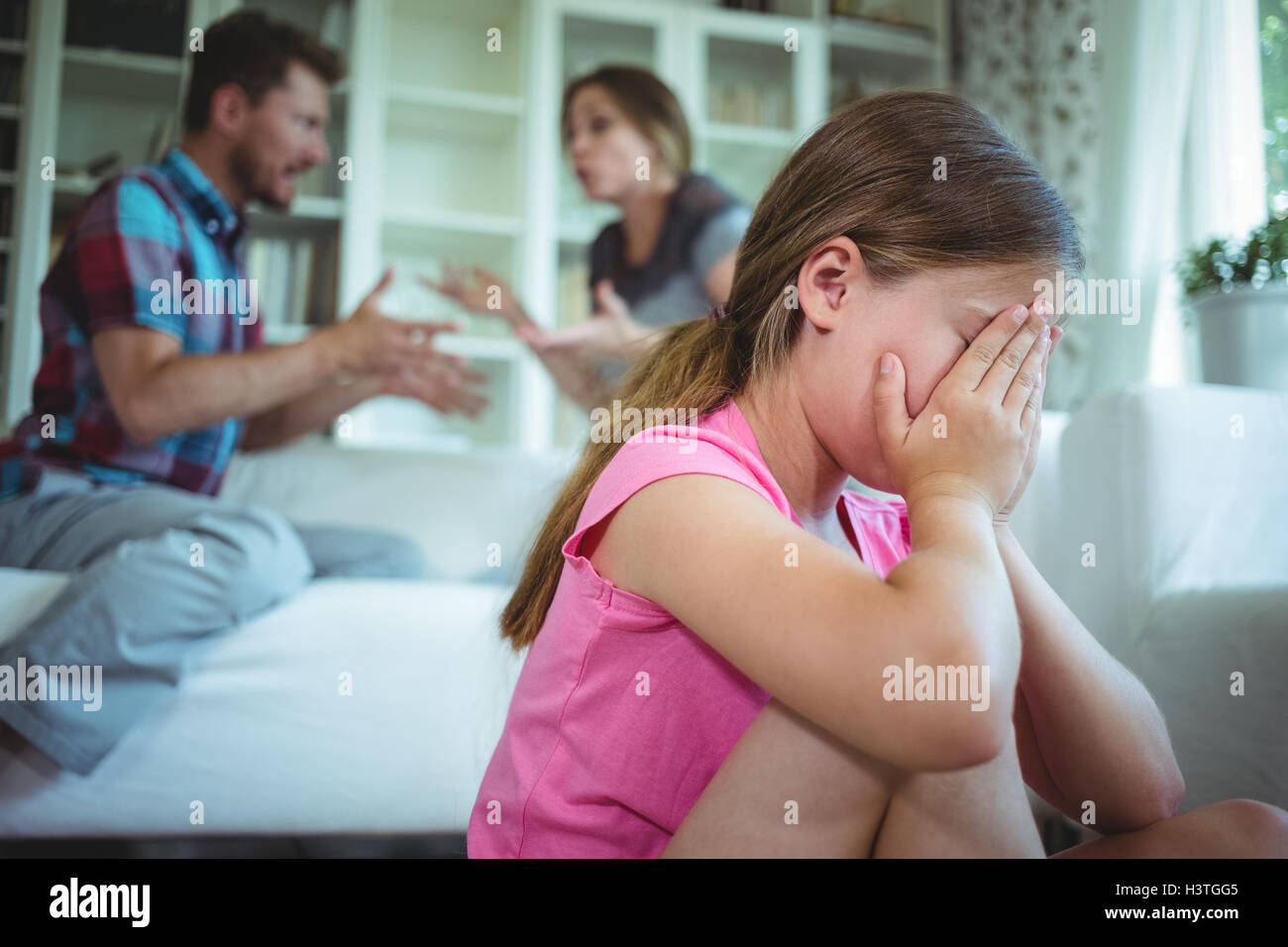 Ragazza triste ascoltando i suoi genitori sostenendo Foto Stock
