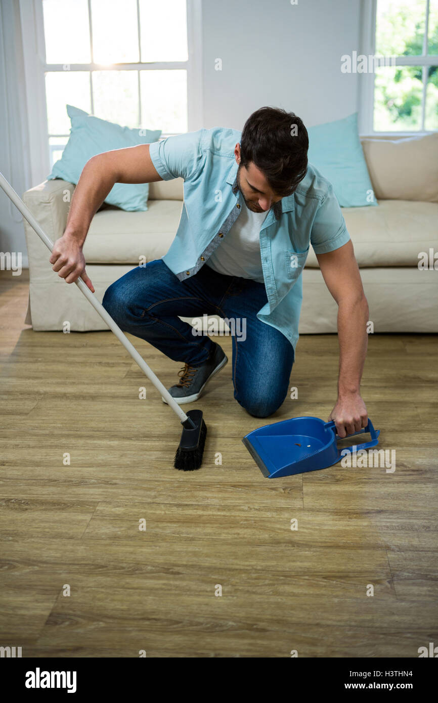 L'uomo la pulizia del pavimento con la scopa e selettore di polvere Foto Stock