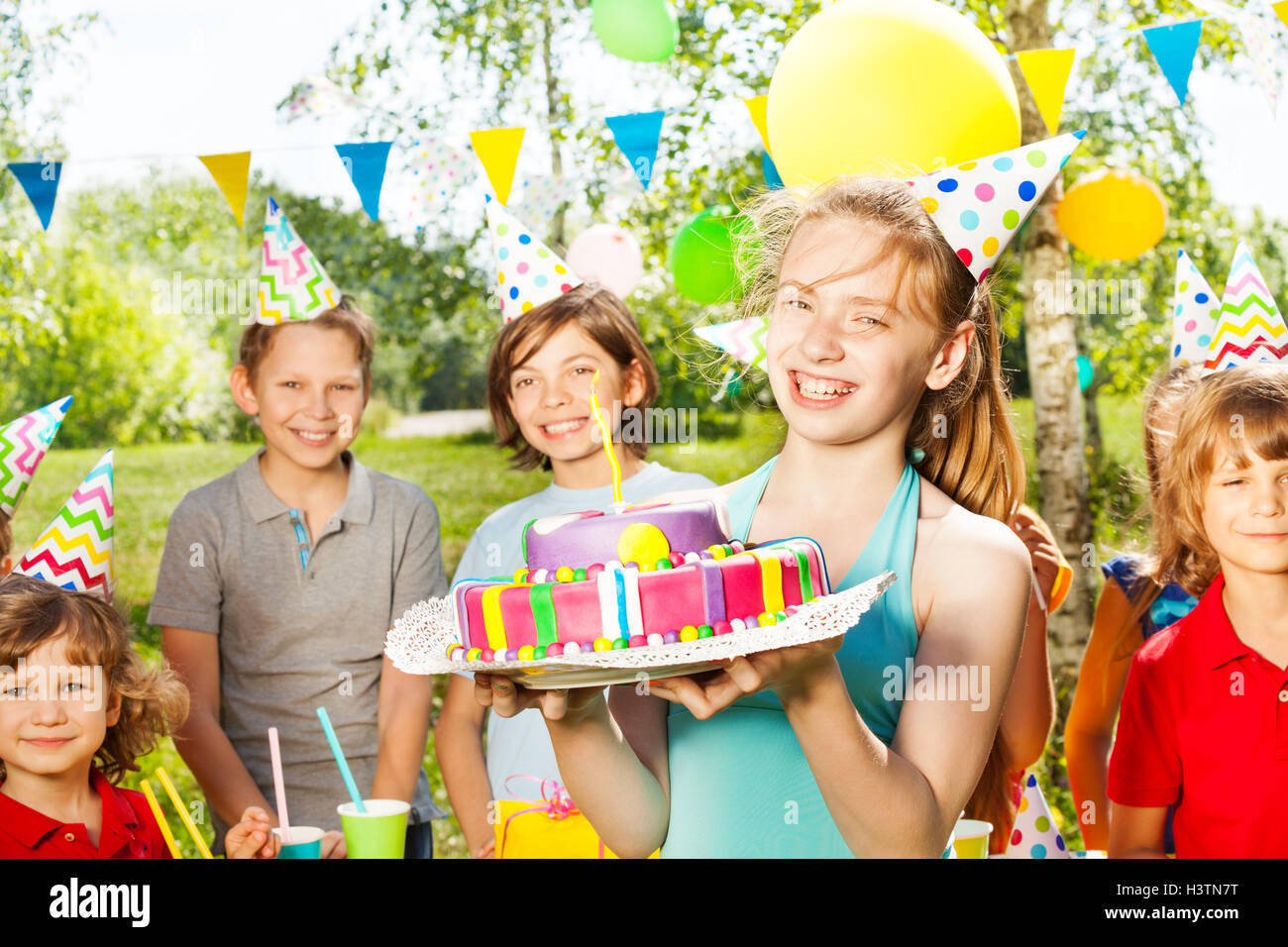 Ritratto di ragazza in party hat holding B-giorno torta Foto Stock