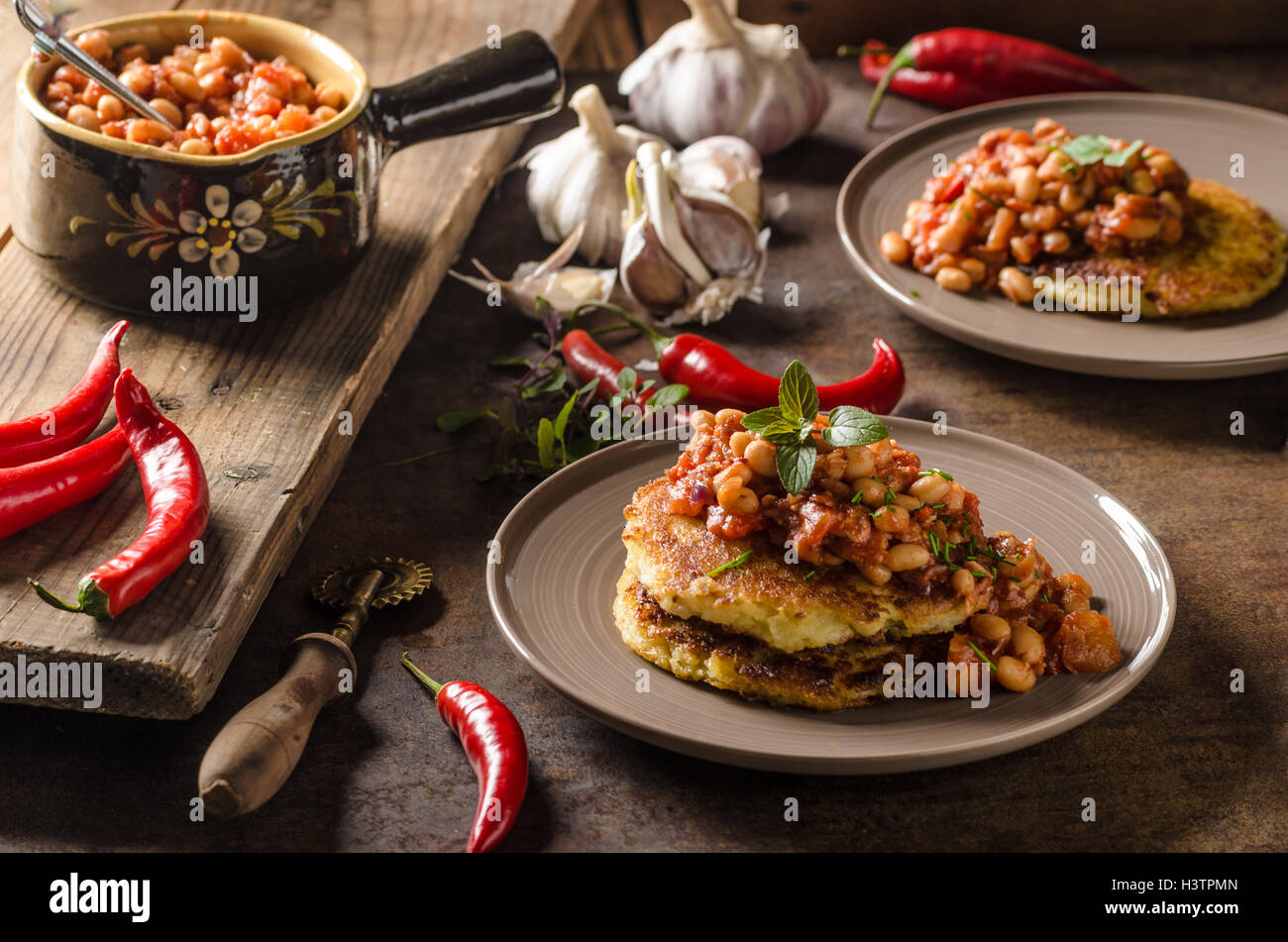 Cuocere i fagioli con soffici torte di patate, speziato e una deliziosa prima colazione Foto Stock