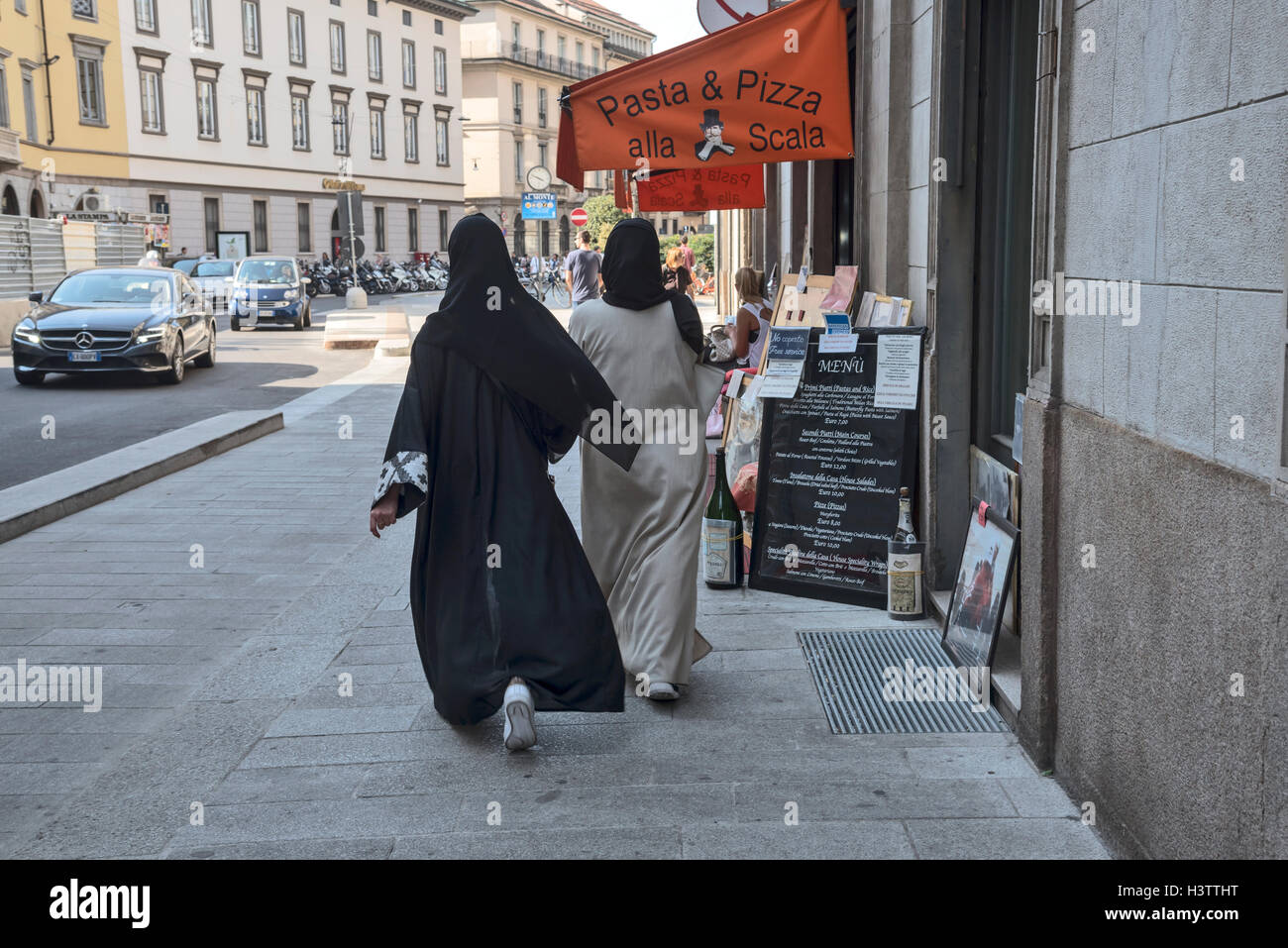 Due giovani donne musulmane in abiti tradizionali sono a piedi lungo via Milano, Italia, Europa Foto Stock