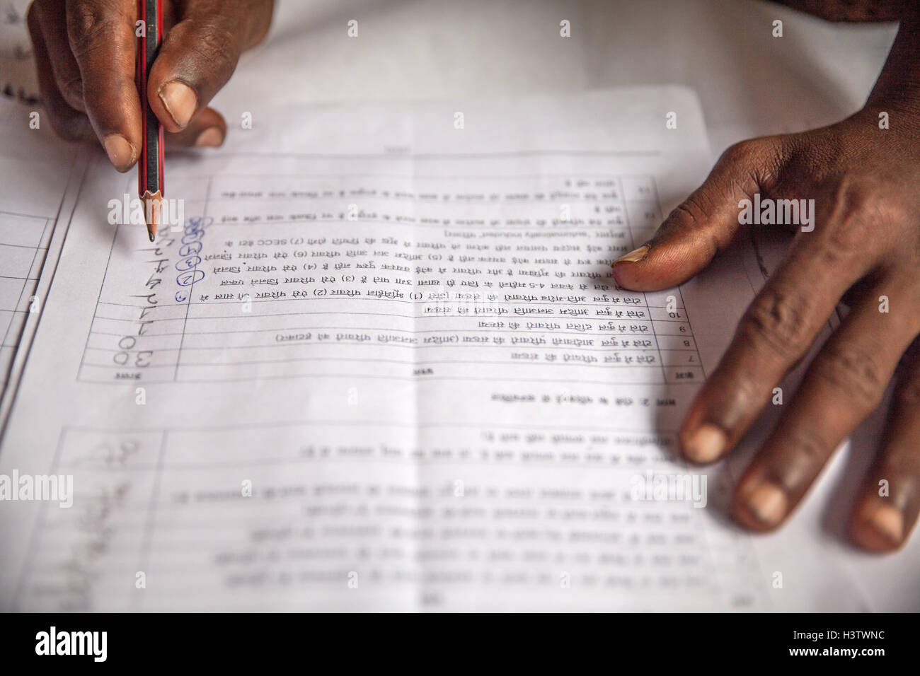 Le mani di un agricoltore in India che compila un'applicazione in lingua hindi per chiedere di infrastrutture di sostegno per il suo villaggio dal Foto Stock