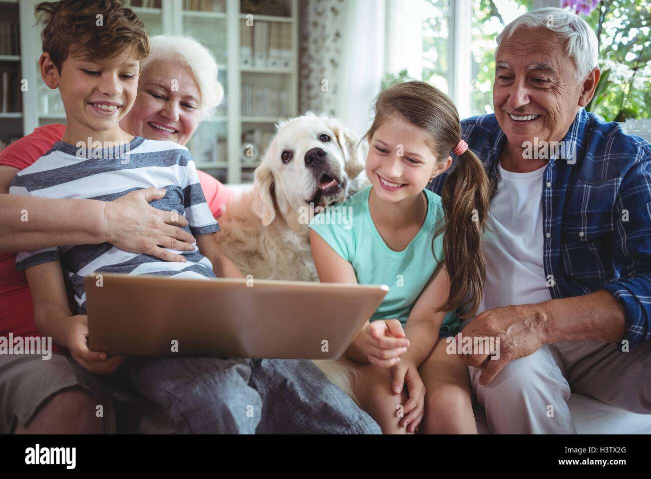 Nonni e nipoti utilizzando laptop in salotto Foto Stock