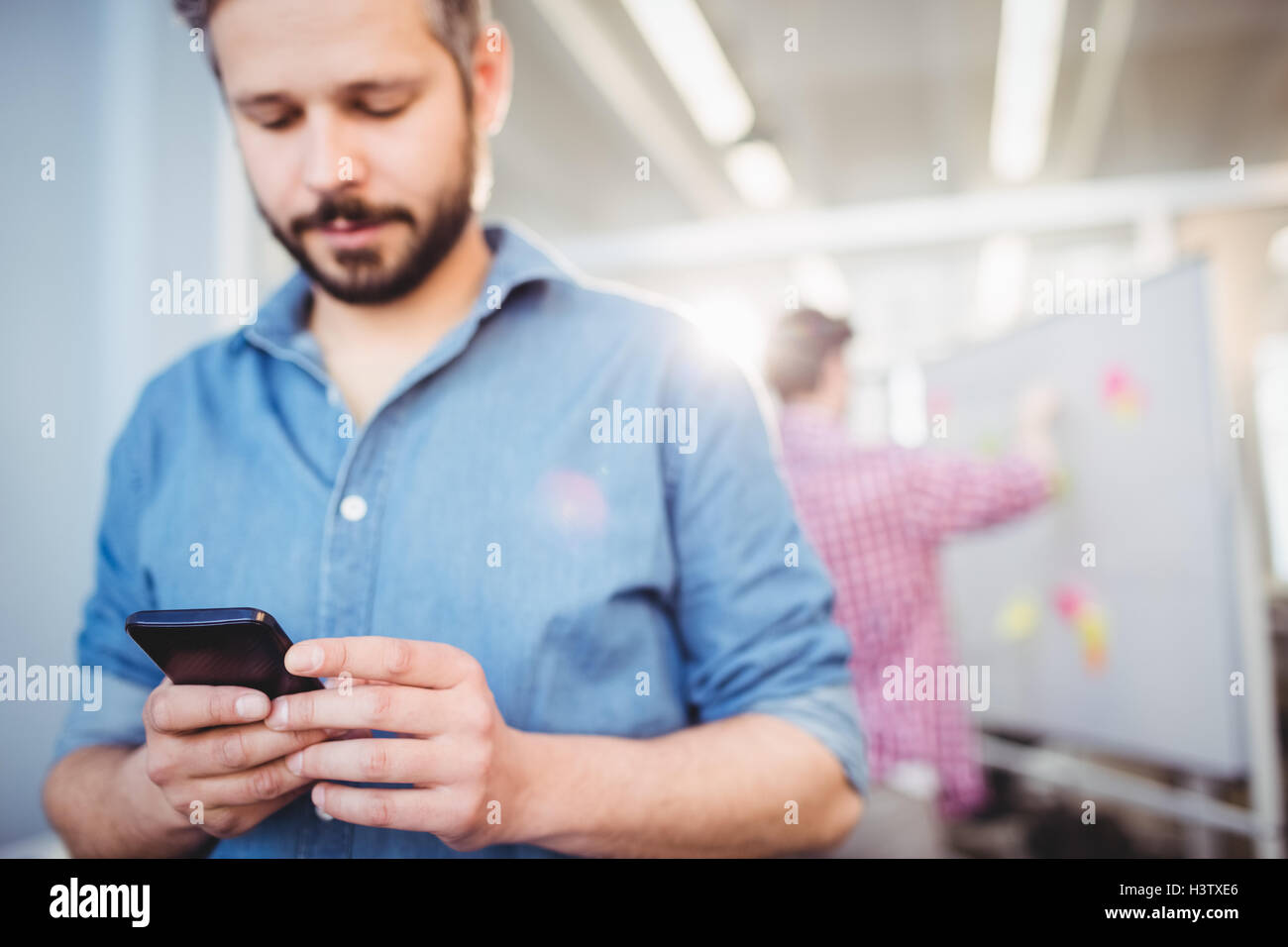 Imprenditore sms sul cellulare presso il creative office Foto Stock
