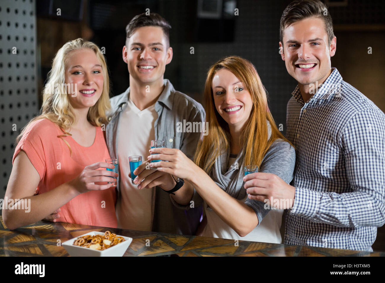 Gruppo di amici in piedi al bancone e avente la tequila scatti Foto Stock