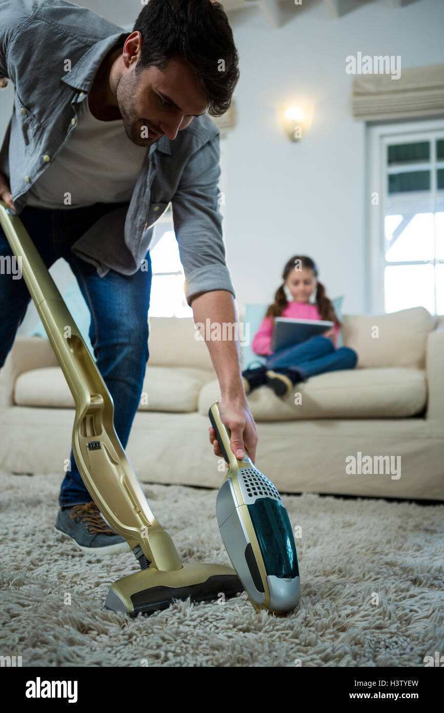 L'uomo la pulizia di un tappeto con un aspirapolvere Foto stock - Alamy