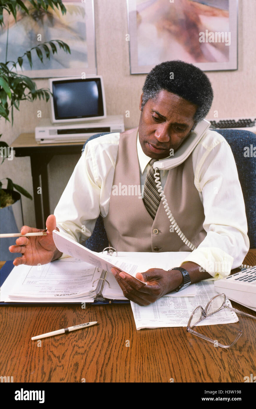 Anni ottanta AFRICAN AMERICAN BUSINESSMAN IN OFFICE parlando al telefono Foto Stock