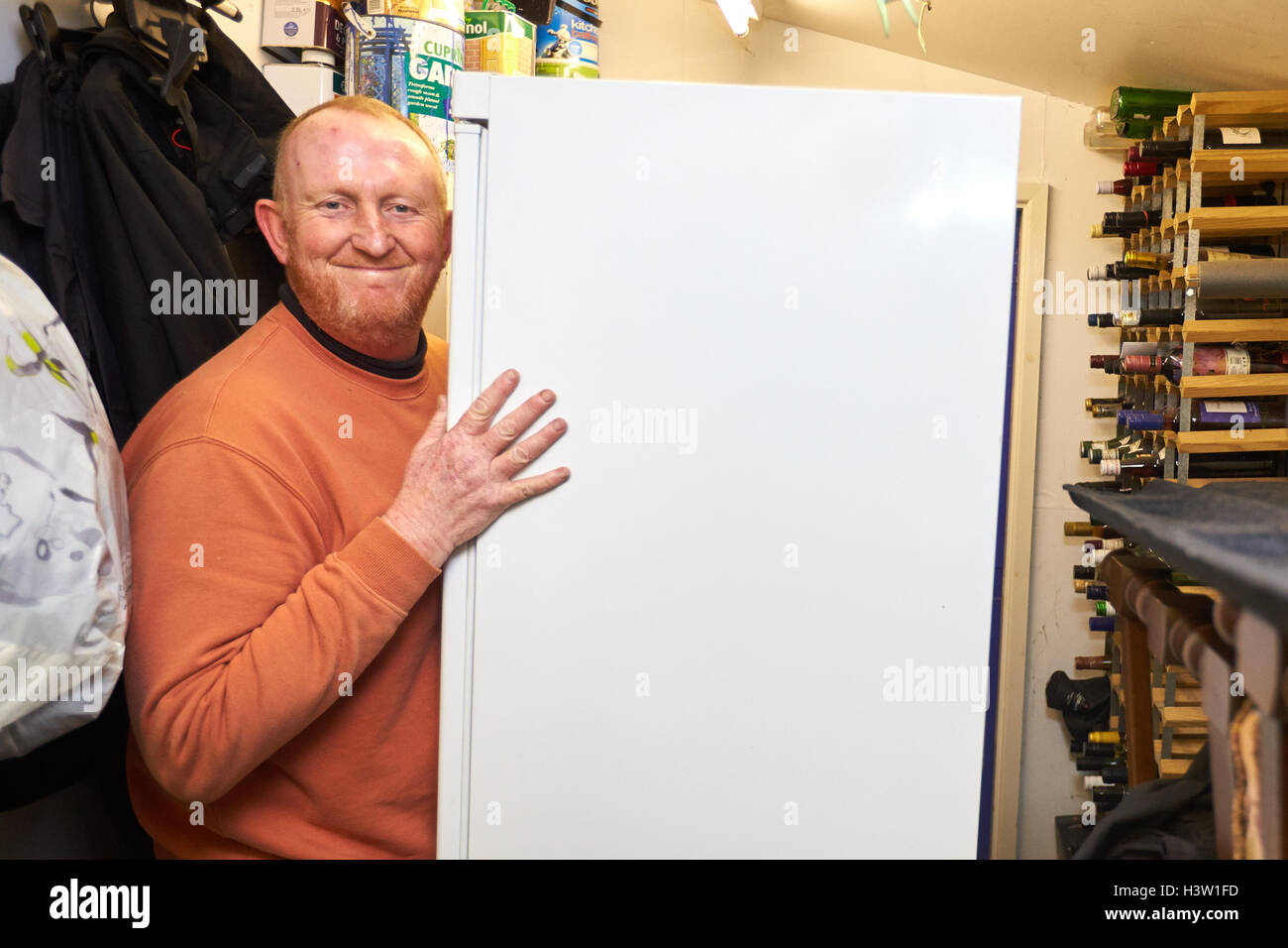 Un uomo che vive in una roulotte sposta il suo bianco merci e altri possedimenti a terra superiore in previsione di inondazioni Foto Stock