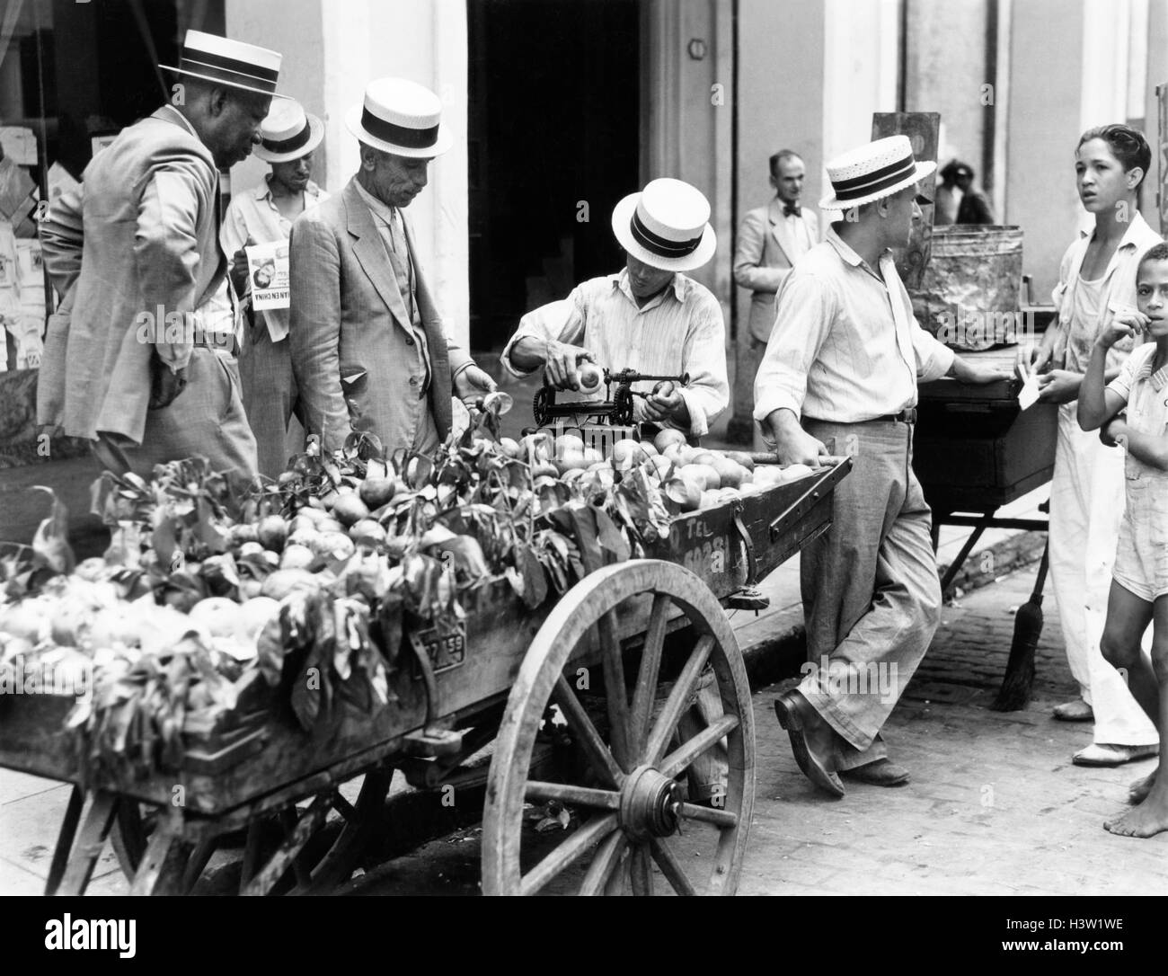 Trenta anni quaranta uomini in cappelli di paglia marciapiede e fornitore APPLE CON CARRELLO HAVANA CUBA Foto Stock