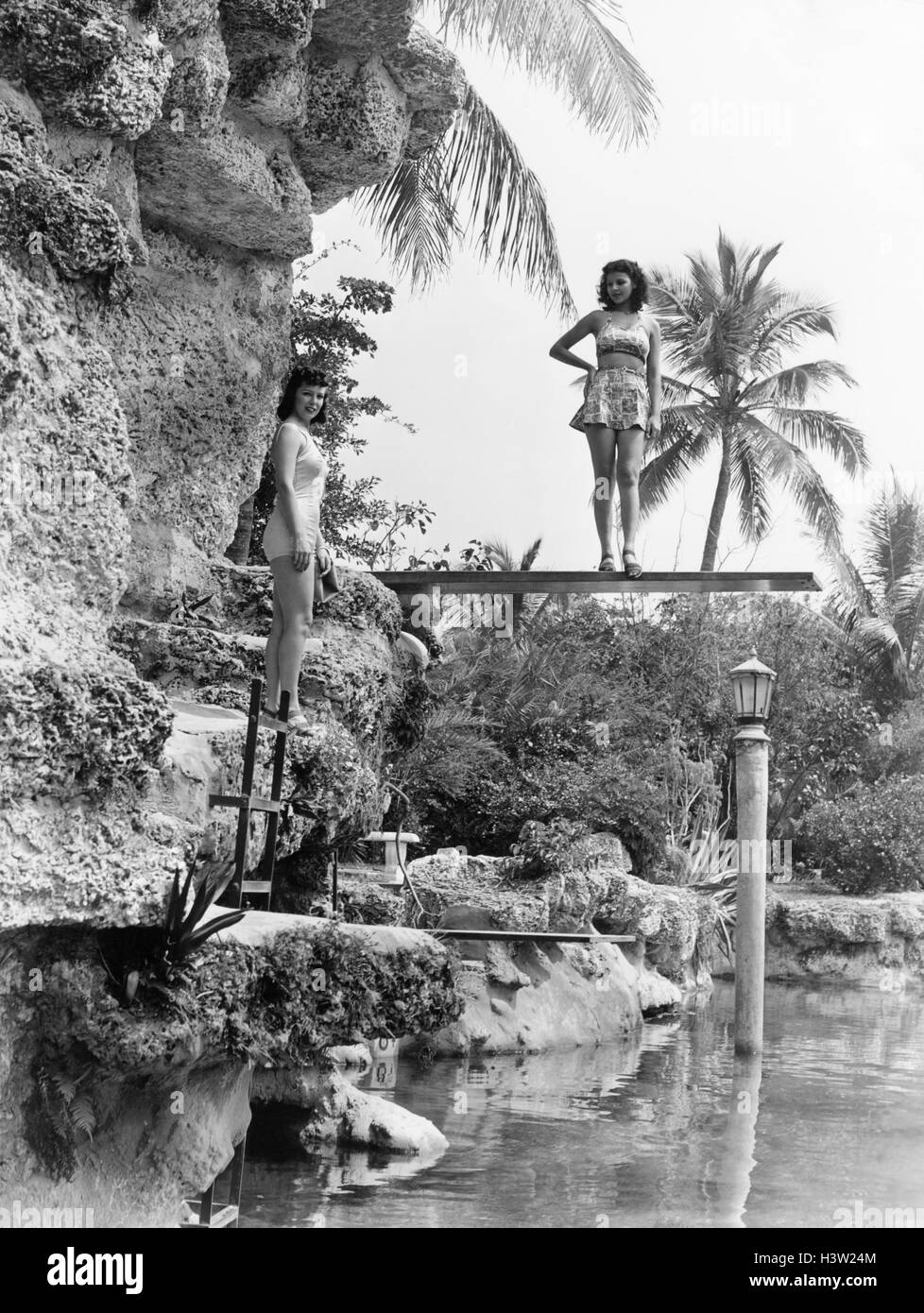1930s 1940s 2 donne in posa sul lato piscina indossando il costume da località tropicali PALME Foto Stock