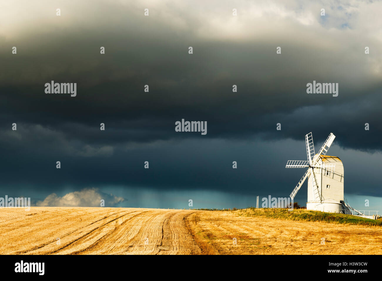 Ashcombe windmill illuminato dal basso nel sole pomeridiano come nuvole temporalesche approccio da nord, East Sussex, Regno Unito Foto Stock