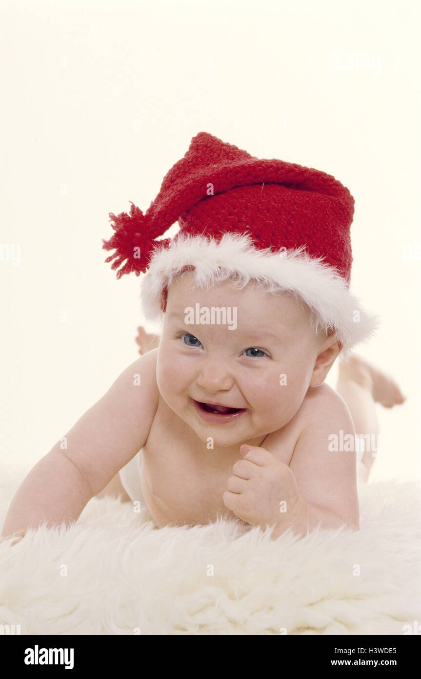 Baby, Santa's hat, ridere bambino, infantile, cappuccio, cappello di Natale rosso-bianco, pelle di agnello, giacciono, softy, comodamente, Natale, yule tide, X-mas, infanzia e innocenza, rivestimento, divertente, umorismo, Natale bambino, ironicamente, felice, studio Foto Stock