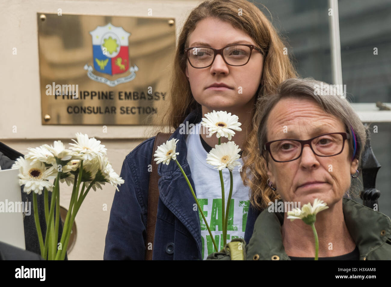 Londra, Regno Unito. Xiii oct, 2016. Womenhold fiori di colore bianco al di fuori dell'Ambasciata delle Filippine alla protesta per consegnare una lettera all'Ambasciatore delle Filippine chiamando per Presidente Rodrigo Duterte per terminare i suoi ripetuti inviti per le forze di polizia e di pubblica per uccidere coloro che utilizzano e trattare la droga e ritirare la sua promessa non vi saranno azioni penali per queste esecuzioni extragiudiziali. Dal momento che egli è venuto a potenza alla fine di giugno vi sono state oltre 3500 tali uccisioni illegali sulle strade. Credito: Peter Marshall / Alamy Live News Foto Stock