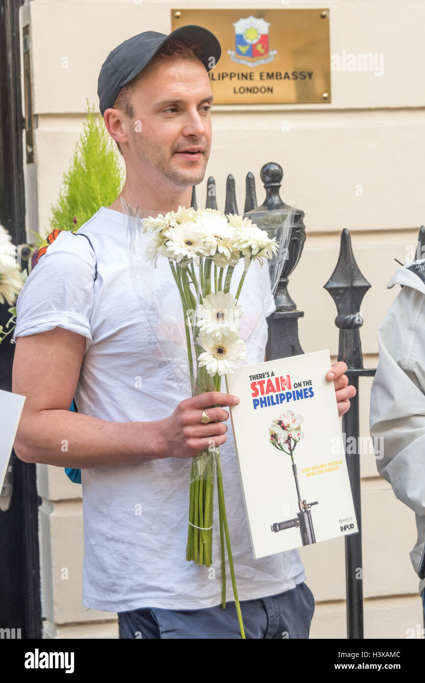 Londra, Regno Unito. Xiii oct, 2016. Un uomo possiede fiori di colore bianco al di fuori della Philipine ambasciata in una protesta per consegnare una lettera all'Ambasciatore delle Filippine chiamando per Presidente Rodrigo Duterte per terminare i suoi ripetuti inviti per le forze di polizia e di pubblica per uccidere coloro che utilizzano e trattare la droga e ritirare la sua promessa non vi saranno azioni penali per queste esecuzioni extragiudiziali. Dal momento che egli è venuto a potenza alla fine di giugno vi sono state oltre 3500 tali uccisioni illegali sulle strade. Credito: Peter Marshall / Alamy Live News Foto Stock