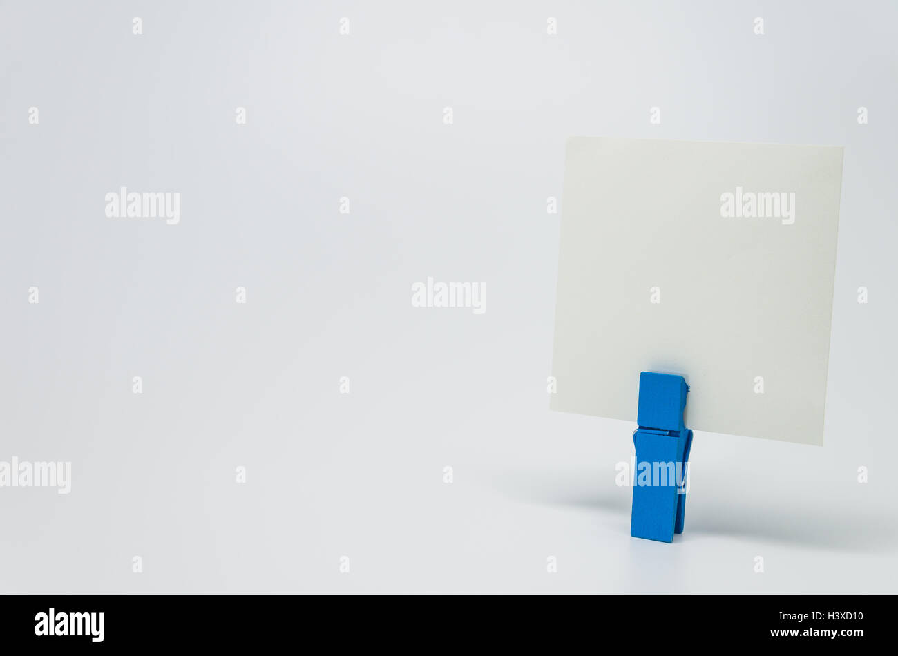 Pezzo di carta Memo serrato da blue clip in legno con sfondo bianco e messa a fuoco selettiva Foto Stock