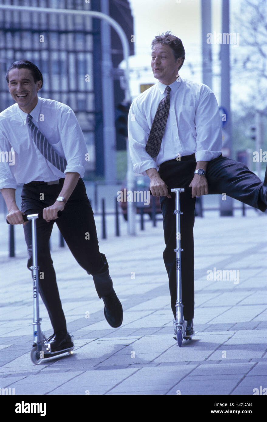 Città, manager, due City-Scooter, ridere, guidare la gioia, esterno, imprenditore, uomo, uomini, gli amici, la gente di affari, scooter, Micro-Scooter, gioia, motion, fuso, divertente, la locomozione, filtro spettrale blu Foto Stock