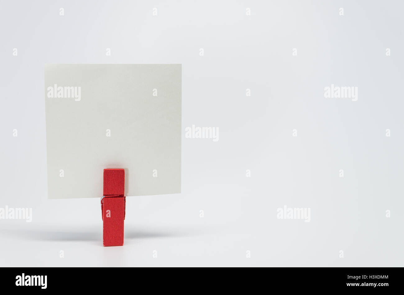 Pezzo di carta Memo serrata dal rosso clip in legno con sfondo bianco e messa a fuoco selettiva Foto Stock