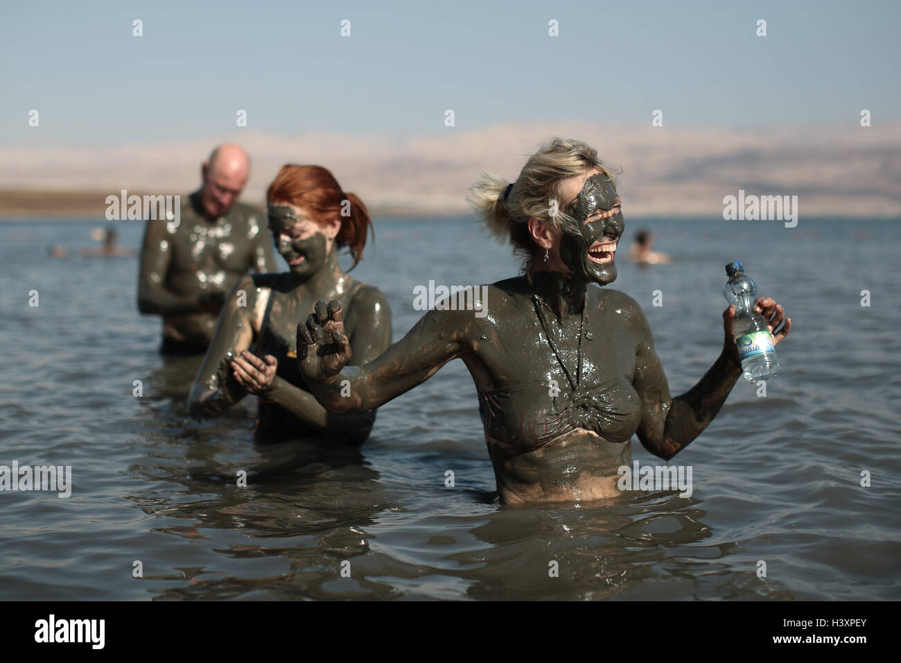 Bagnanti nel Mar Morto coprirsi di fango che ha fama di avere effetti benefici per la pelle. Da una serie di phot Foto Stock