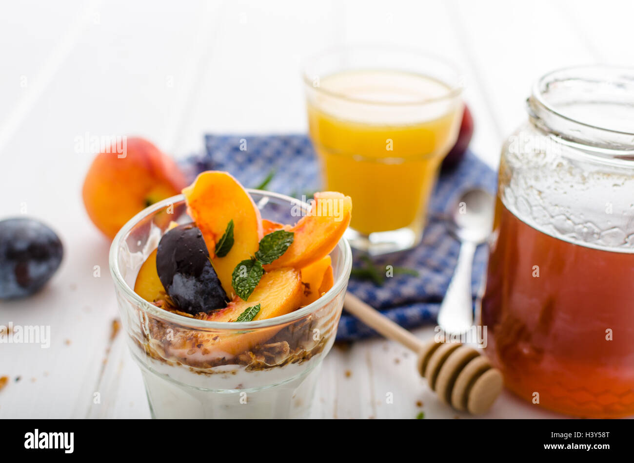 Lo yogurt greco con frutta fresca e granola con miele, succo di frutta fresco Foto Stock