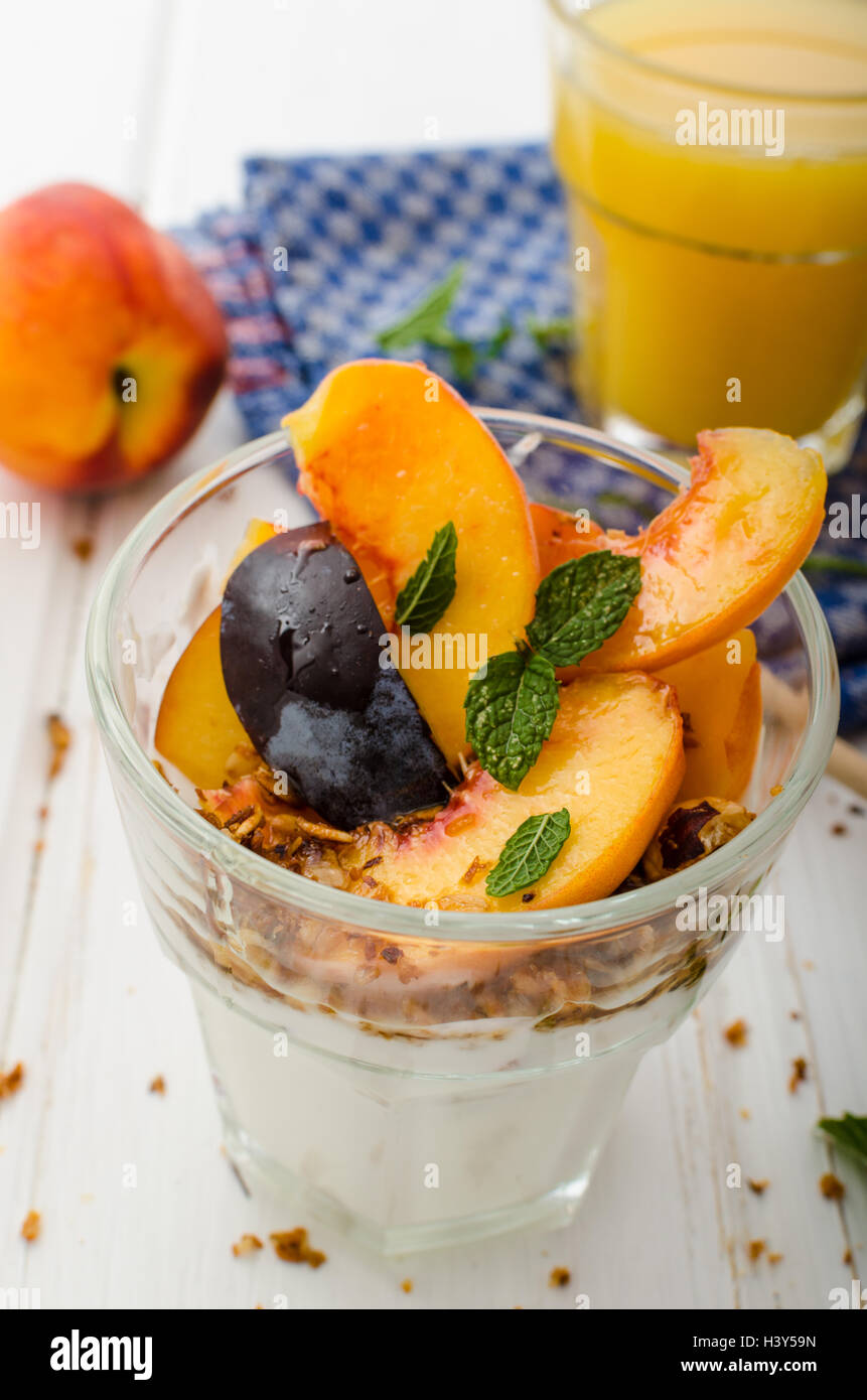 Lo yogurt greco con frutta fresca e granola con miele, succo di frutta fresco Foto Stock
