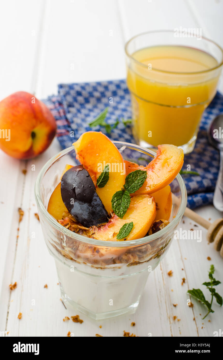 Lo yogurt greco con frutta fresca e granola con miele, succo di frutta fresco Foto Stock