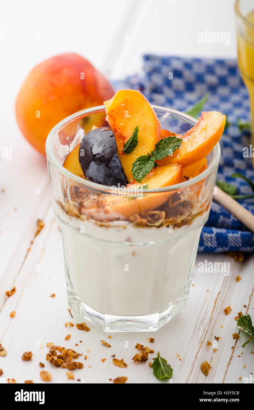 Lo yogurt greco con frutta fresca e granola con miele, succo di frutta fresco Foto Stock