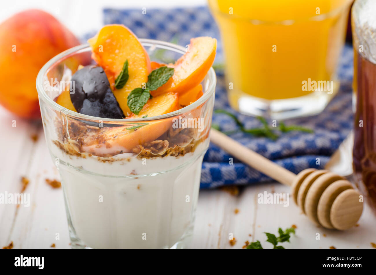 Lo yogurt greco con frutta fresca e granola con miele, succo di frutta fresco Foto Stock