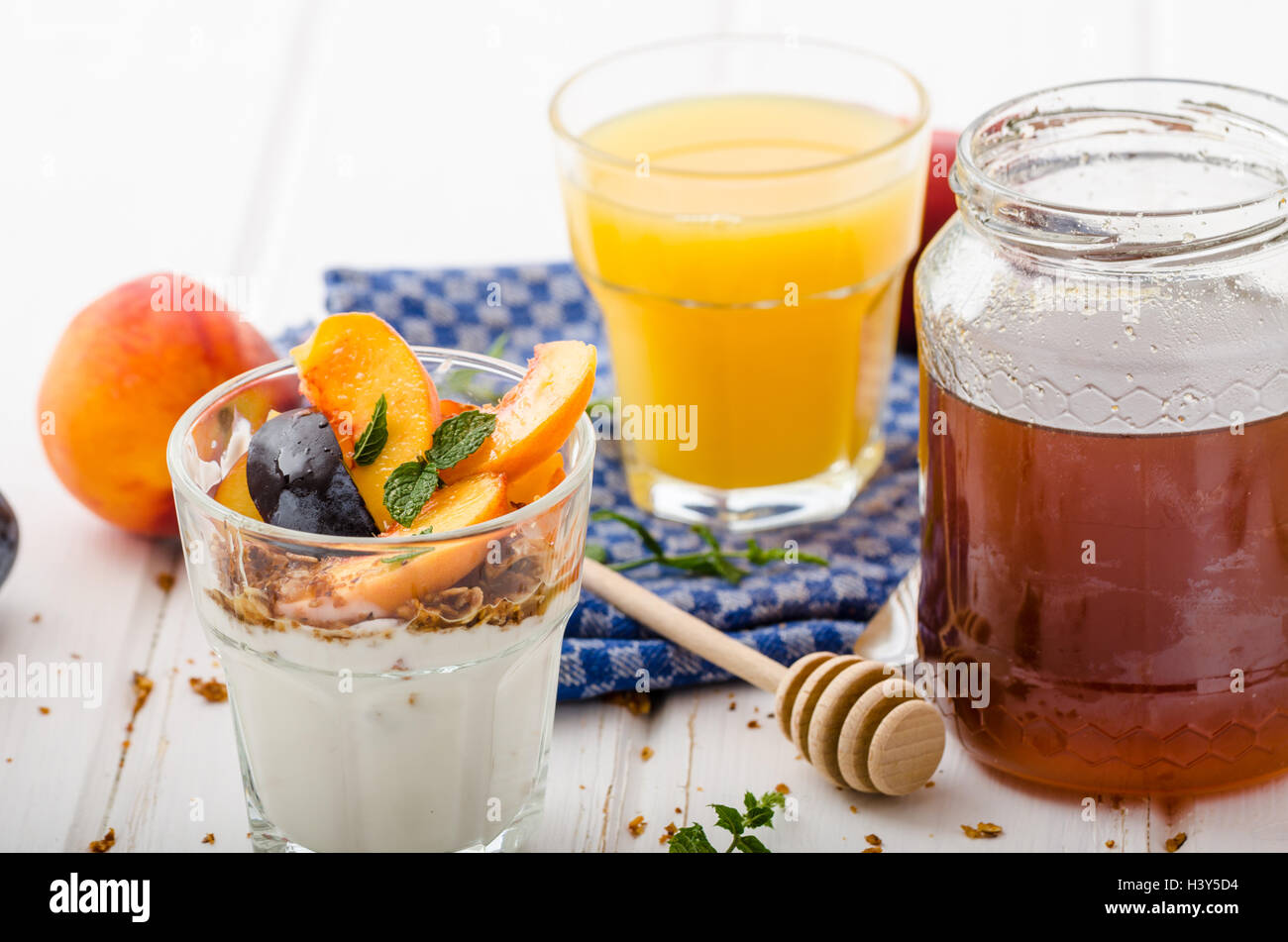 Lo yogurt greco con frutta fresca e granola con miele, succo di frutta fresco Foto Stock