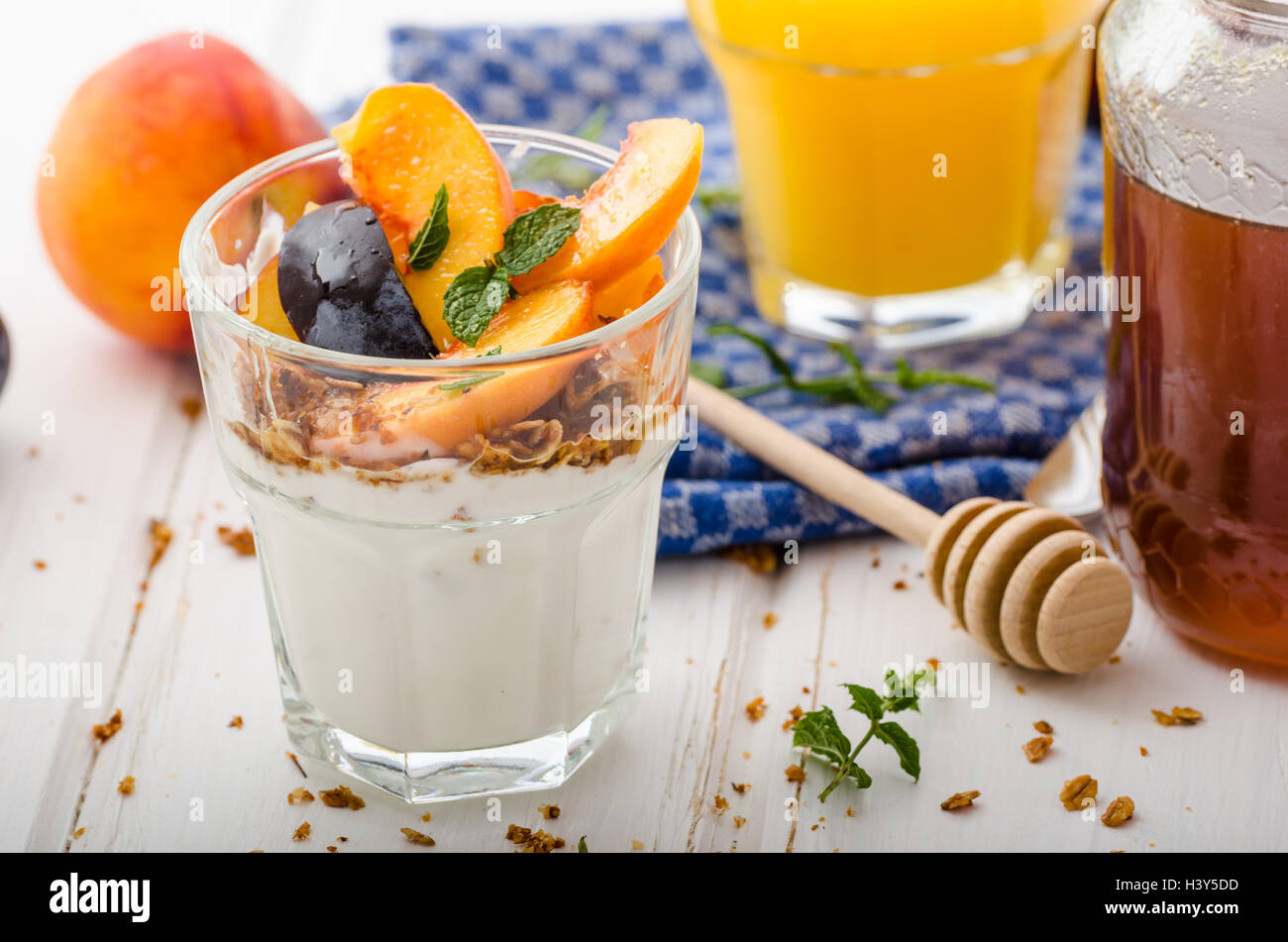Lo yogurt greco con frutta fresca e granola con miele, succo di frutta fresco Foto Stock