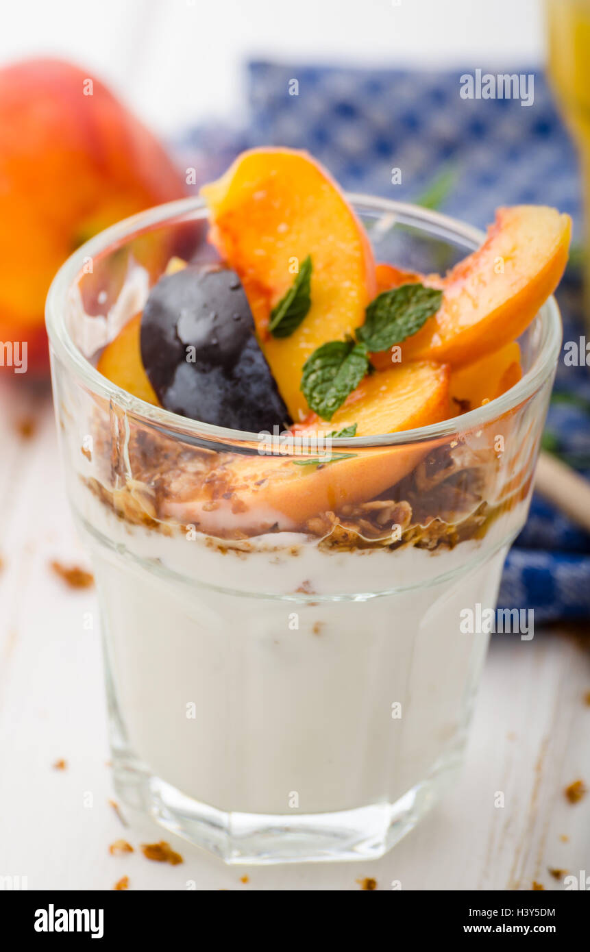 Lo yogurt greco con frutta fresca e granola con miele, succo di frutta fresco Foto Stock
