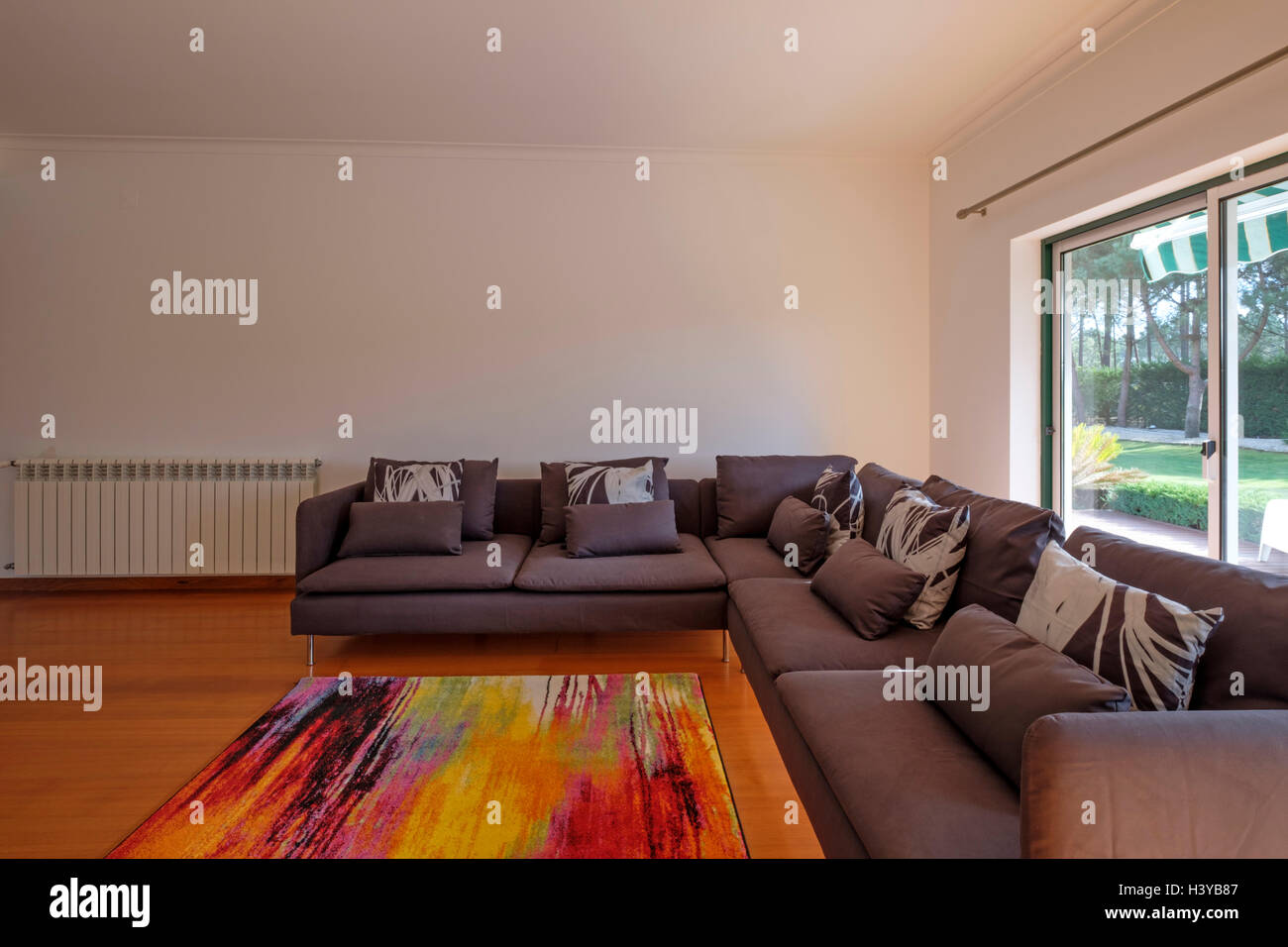 Moderno soggiorno con grande divano marrone e luminosa grande finestra Foto Stock