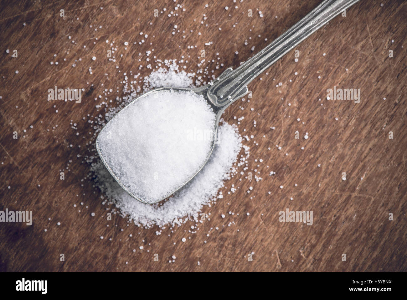 Sale su un cucchiaio in stretta verso l'alto. Tavolo in legno come sfondo con copia spazio. Foto Stock