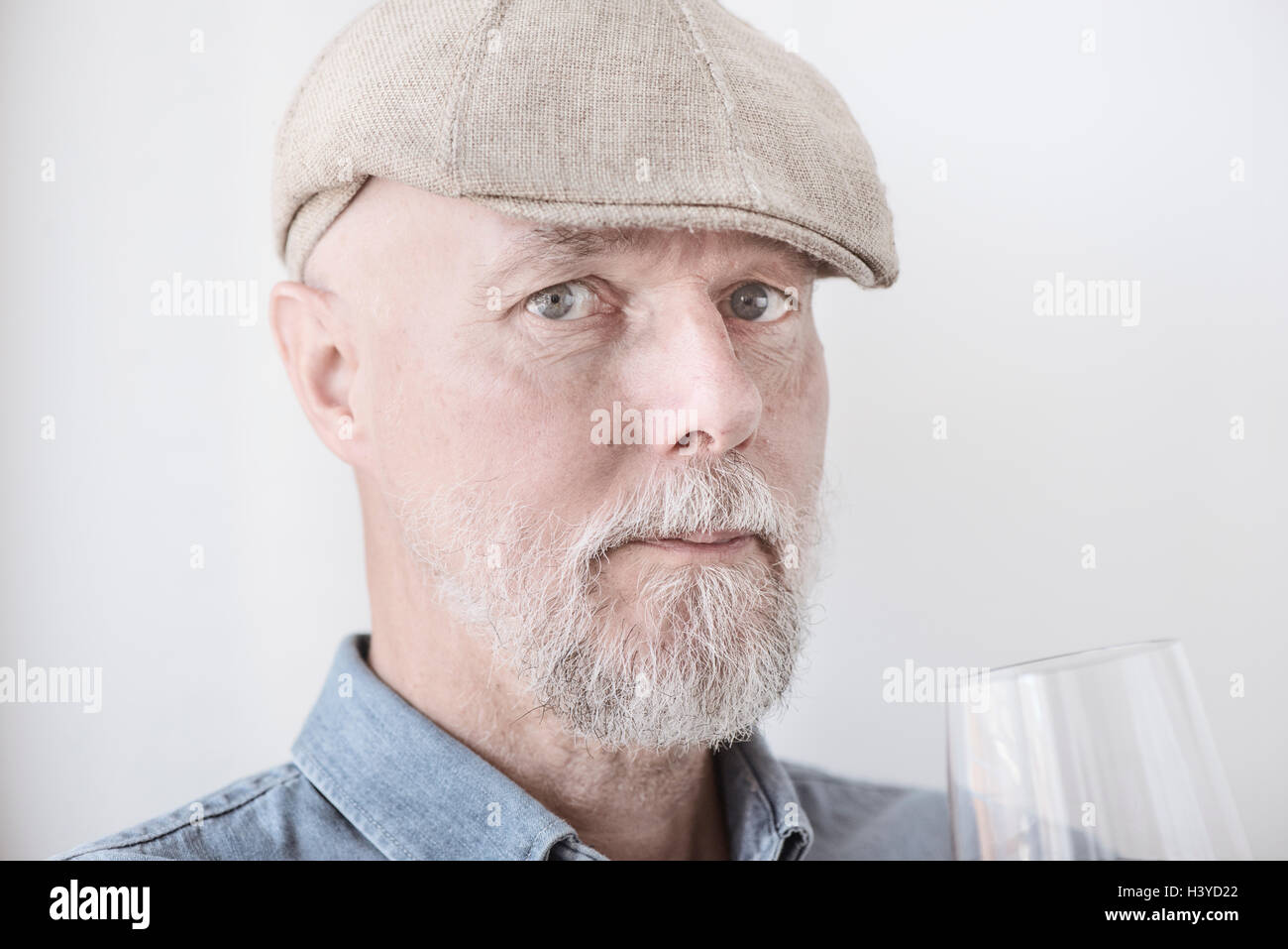 Il vecchio uomo in trattenimento tappo di vetro di vino. Guardando la fotocamera con espressione seria. Foto Stock