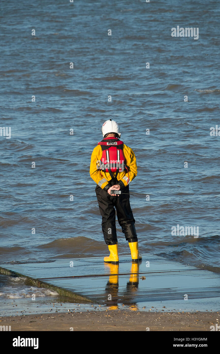 Unico membro della Royal National scialuppa di salvataggio Institute in piedi vicino al mare a Cleethorpes, North East Lincolnshire, Regno Unito Foto Stock